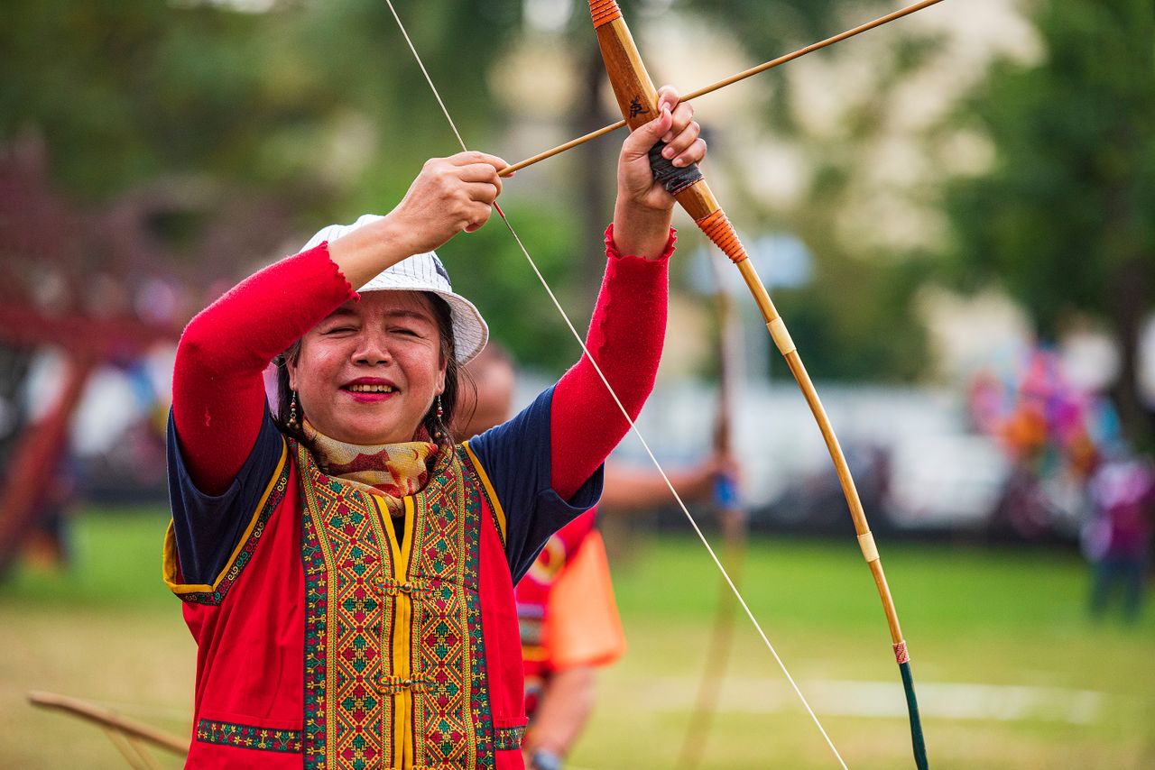 Asian woman skillfully aiming and enjoying traditional archery outdoors in Taiwan.