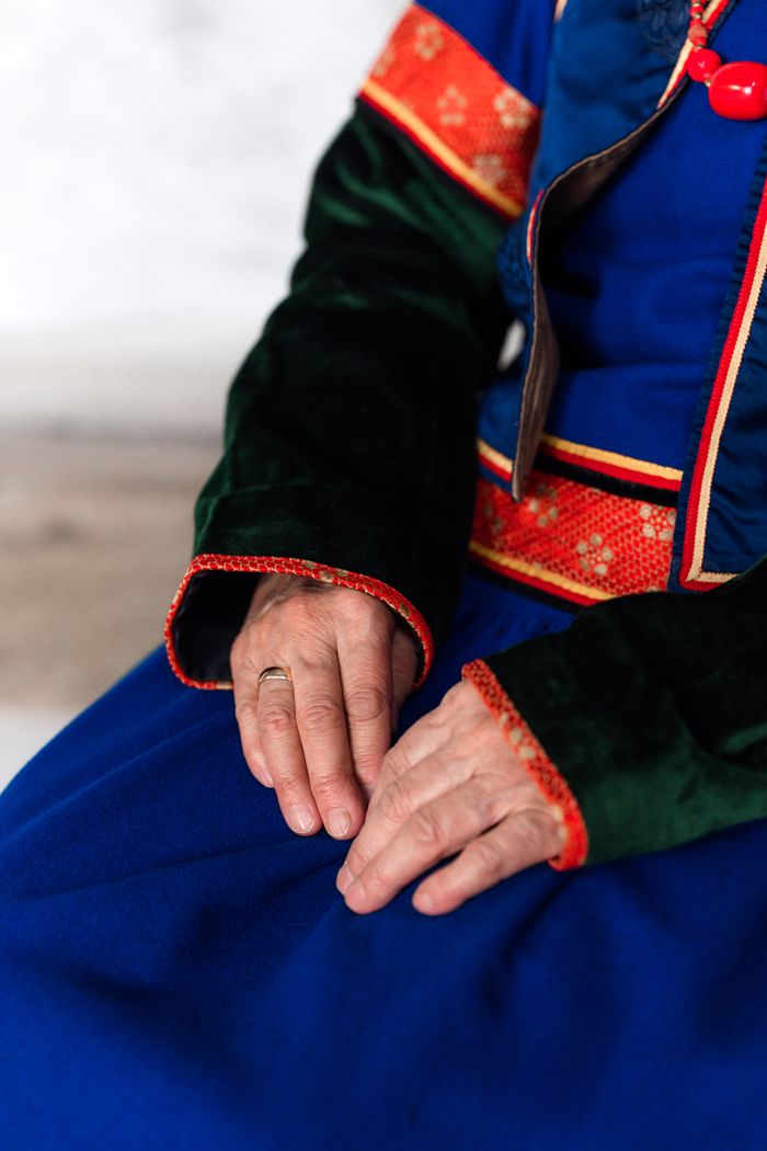 Detailed view of hands resting on traditional Mongolian clothing showcasing vibrant colors and embroidery.